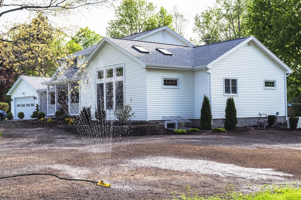 Watering newly seeded ground outside a house